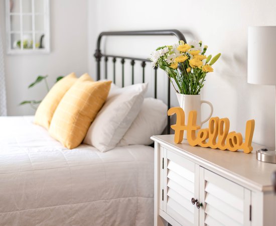 Cheerful-hello-sign-in-clean-and-bright-bedroom-with-yellow-accents